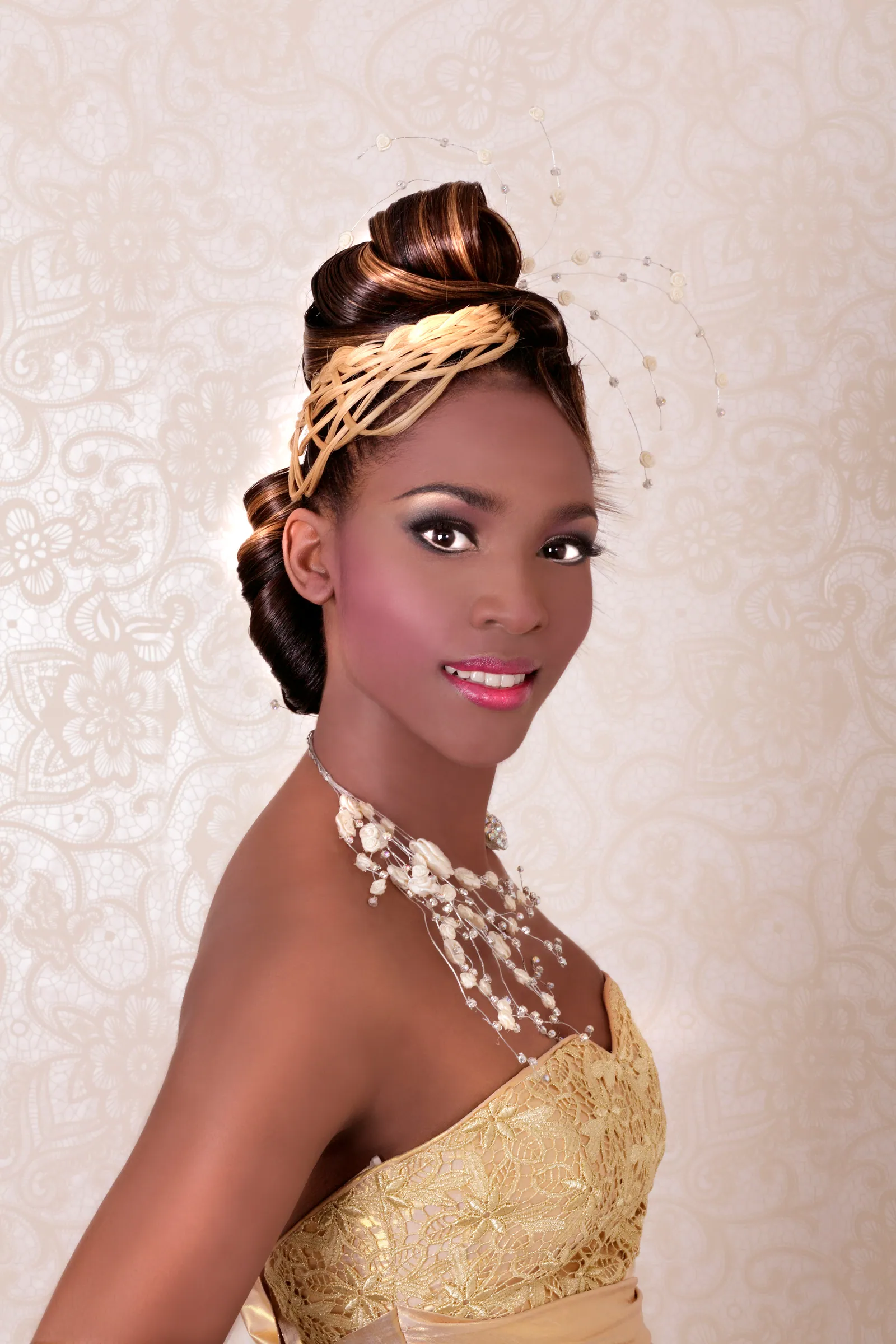 Bride with a high, twisted updo wrapped in gold, wearing a pearl necklace