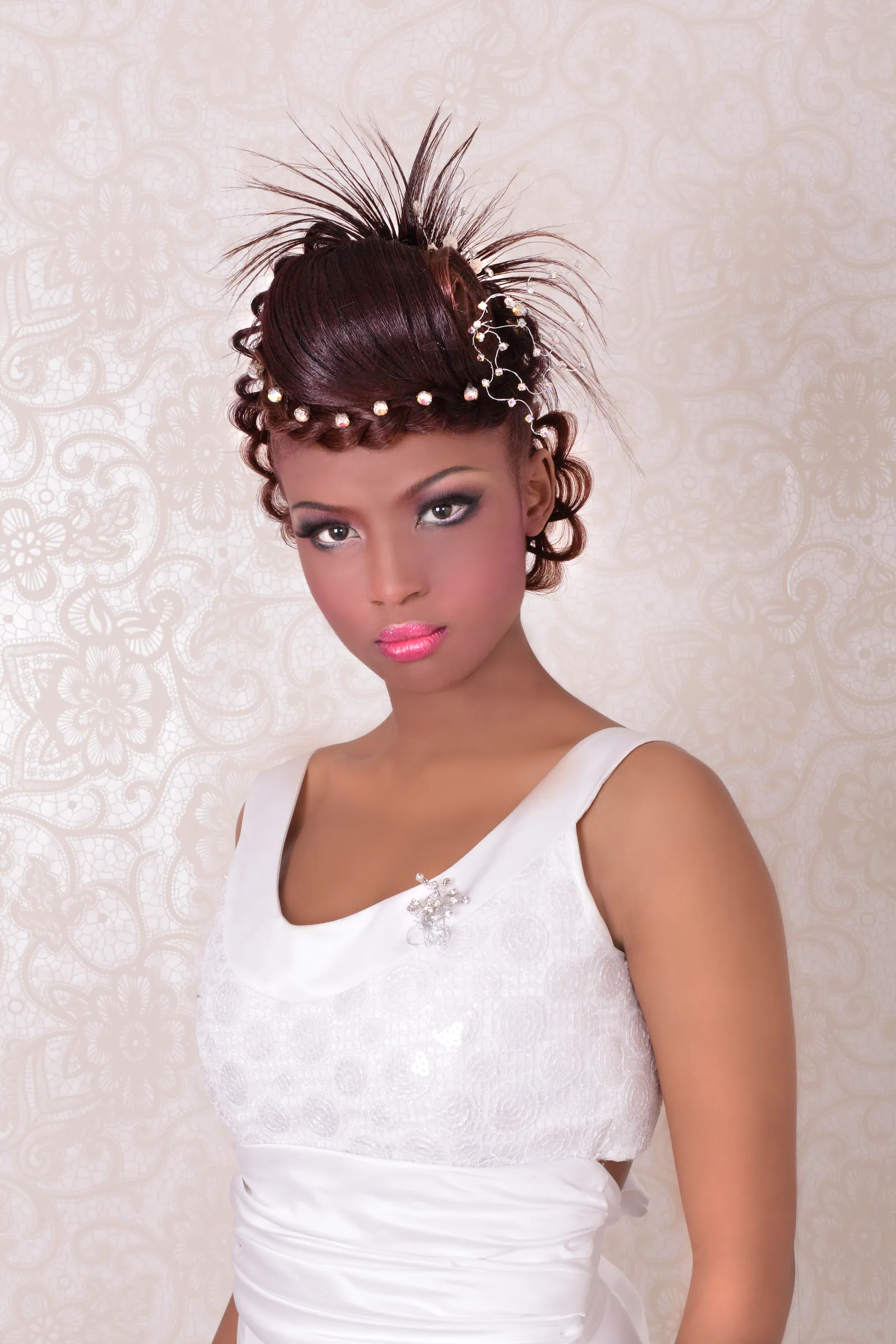 Bride with pinned curls threaded with pearls and a feathered spray