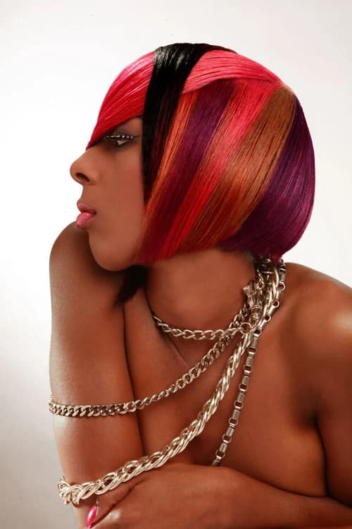 Bob coloured in bands of red, pink, copper and black, in profile with gold chains
