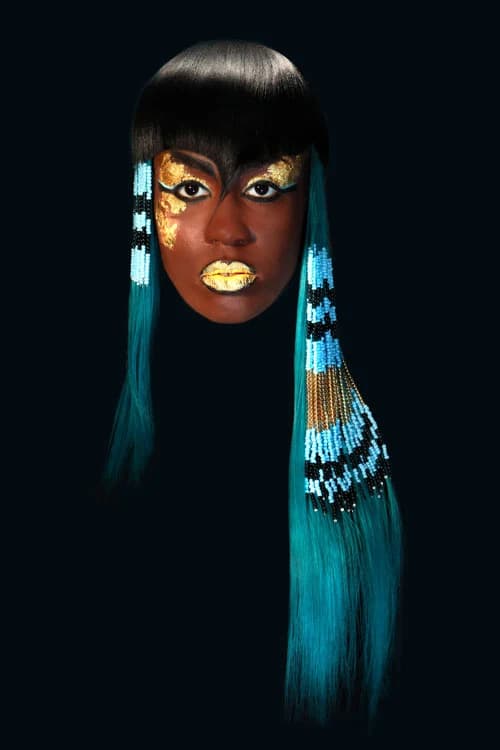 Black fringe with long turquoise beaded lengths, and gold face paint